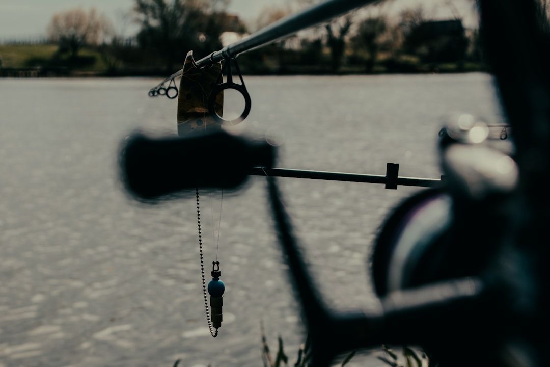 Nærbilde av en fiskestang med lett utstyr satt opp ved et stille vann.